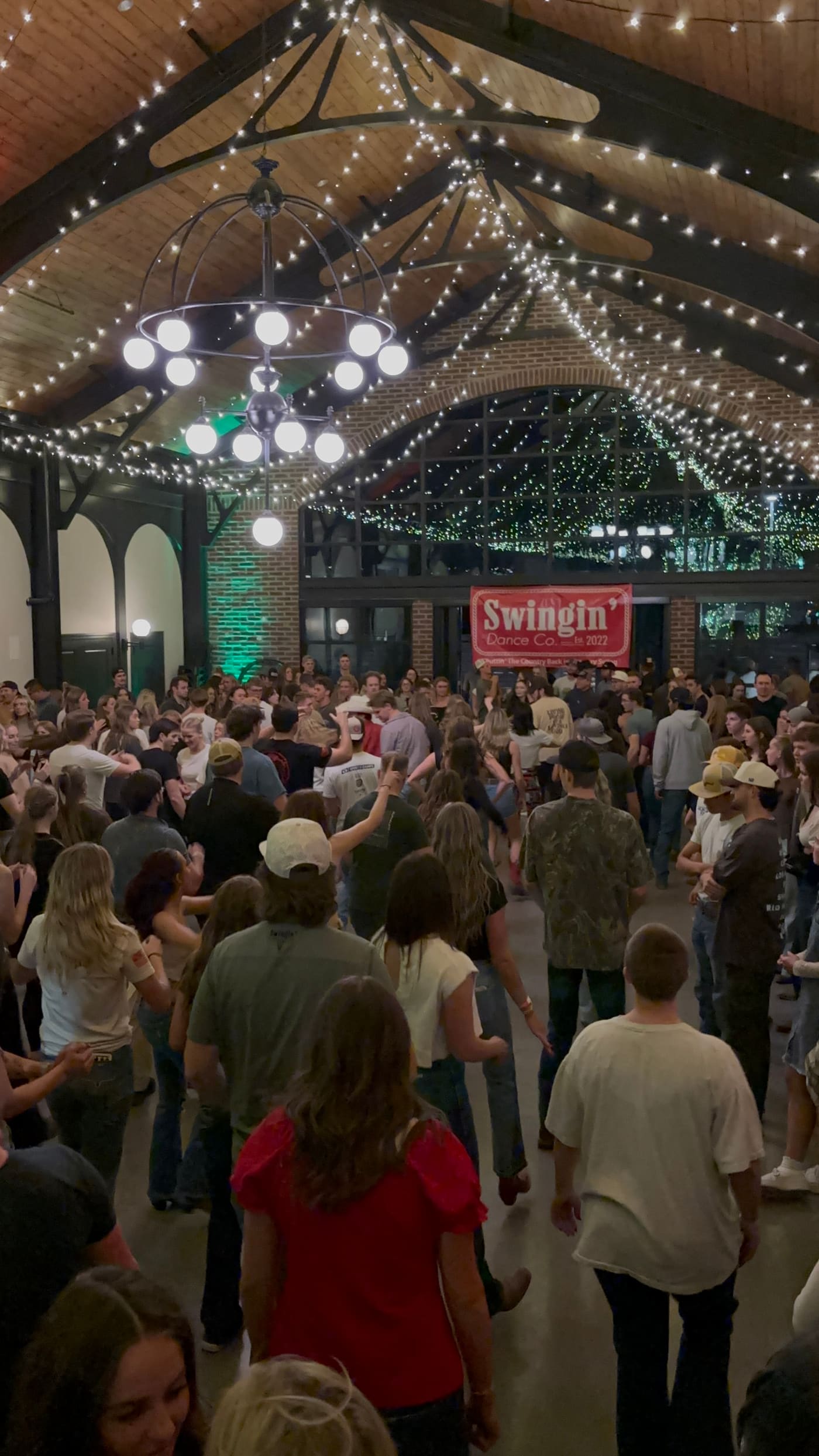 Hundreds of dancers filling Grove Station under string lights and chandelier