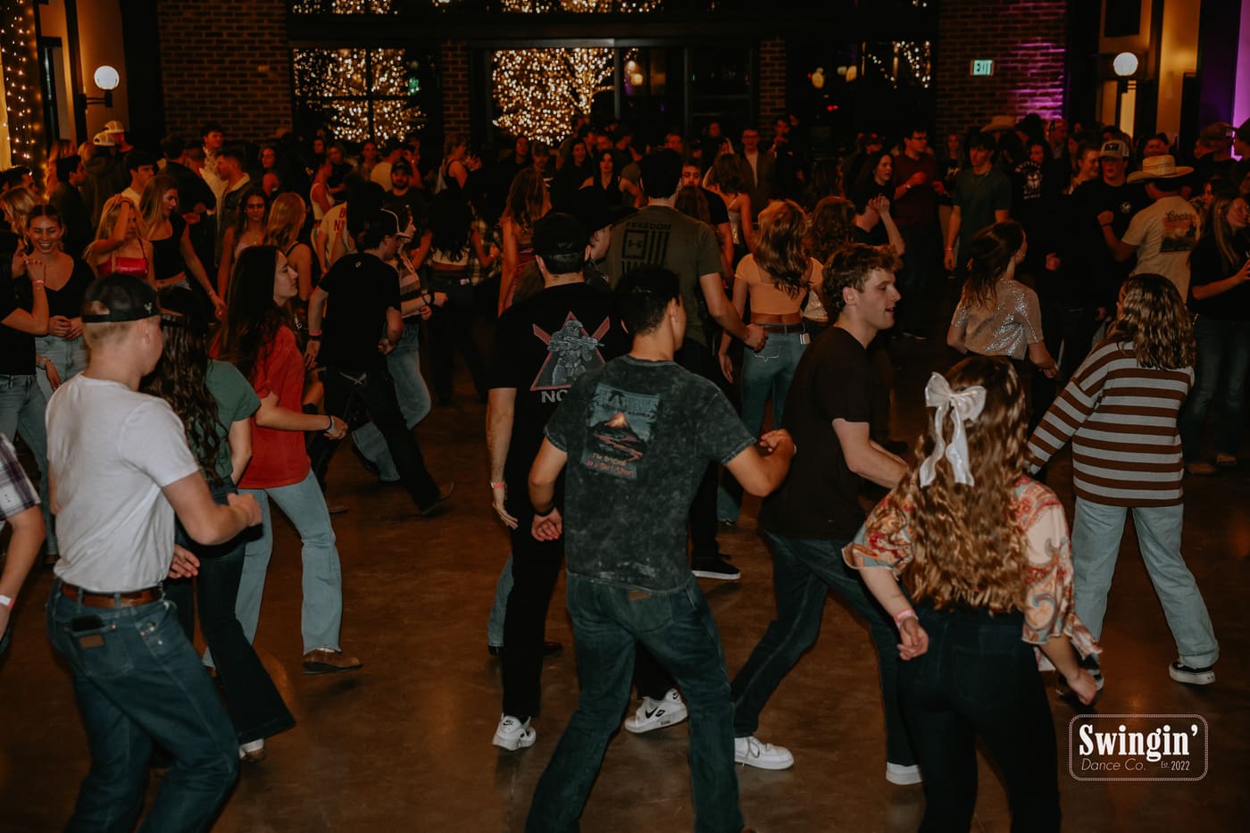 Packed line dance at Grove Station with Swingin Dance Co banner