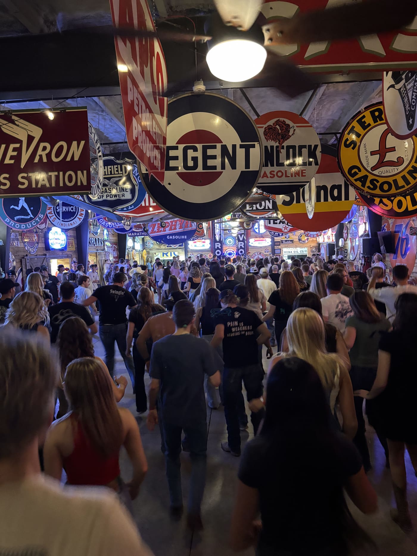Massive crowd dancing at Sparks Museum under vintage gas station signs