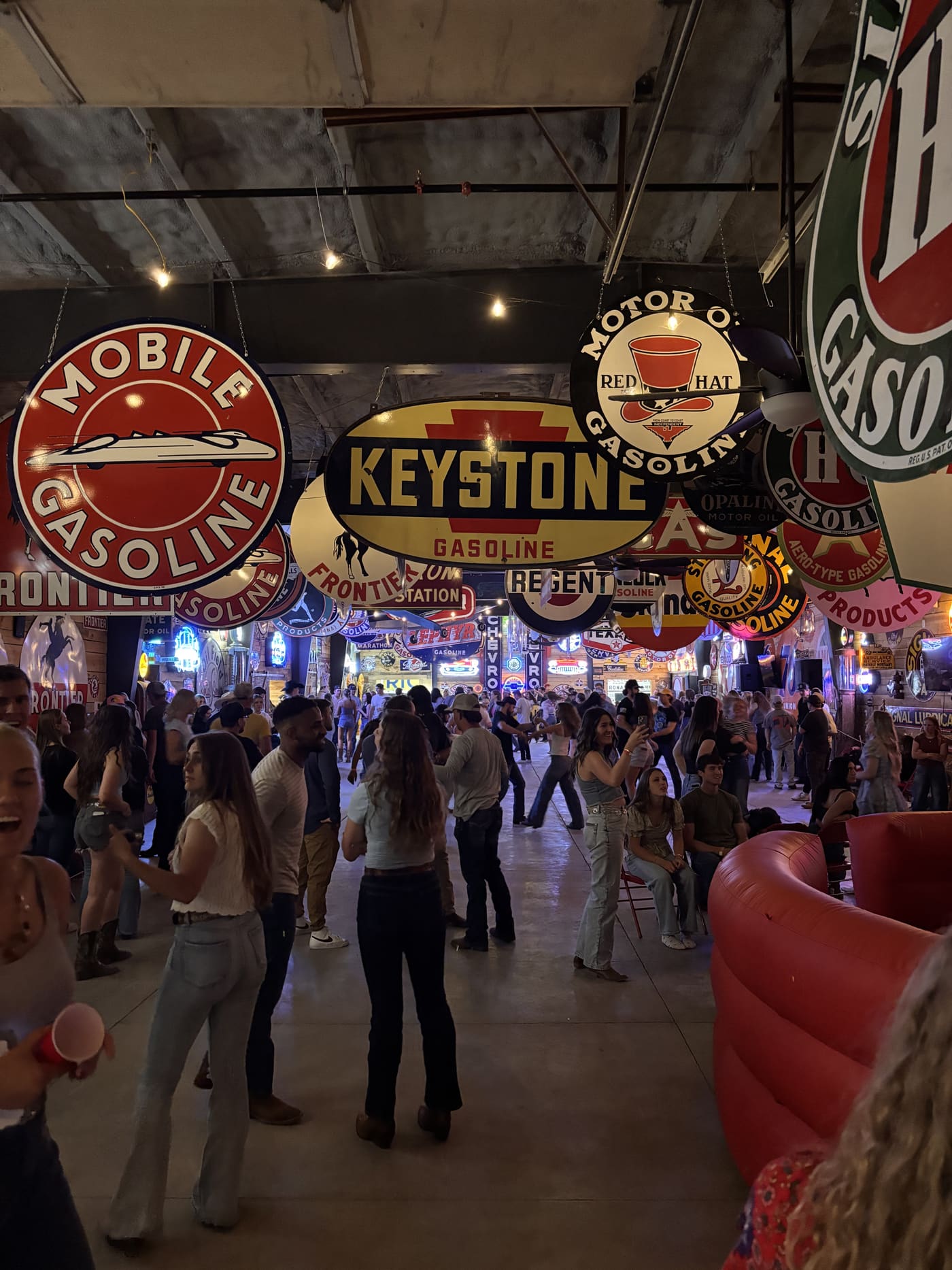 Dancers filling the floor at Sparks Museum under Keystone and Mobile gasoline signs